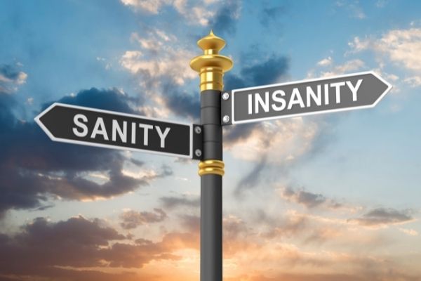 in image of a crossroad sign with two street signs that read sanity and insanity with a sky background and sun setting.